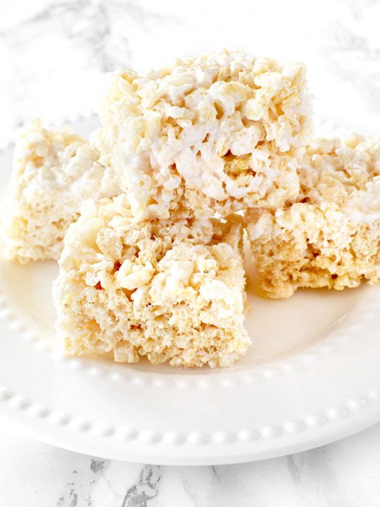 Dairy Free Rice Krispie Treats stacked on a white plate on a white marble counter