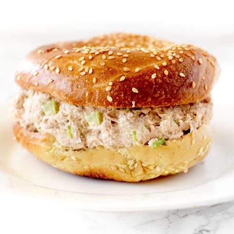 Tuna Salad in a bagel on a white plate on a white counter