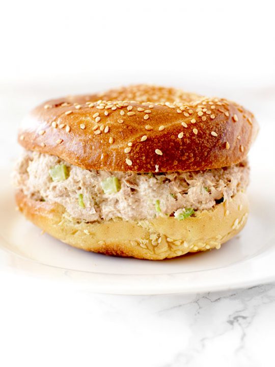 Tuna Salad in a bagel on a white plate on a white counter