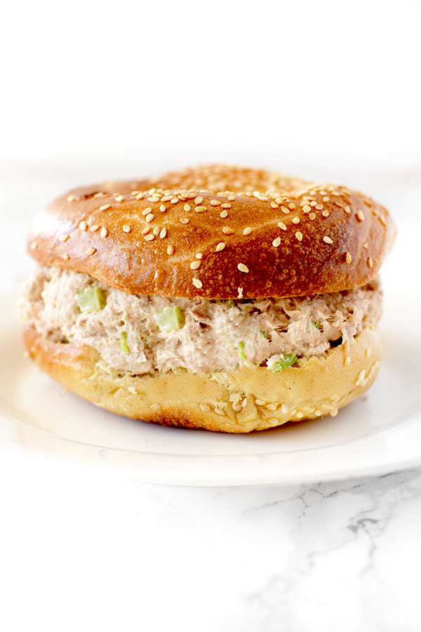 Tuna Salad in a bagel on a white plate on a white counter