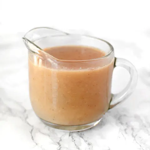 Dairy free gravy in a glass gravy boat on a white marble counter