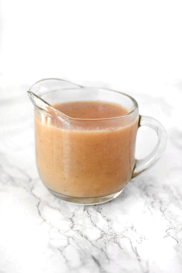 Dairy free gravy in a glass gravy boat on a white marble counter