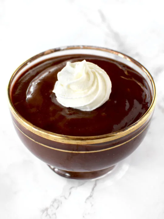 Chocolate pudding in a glass bowl on a white marble counter