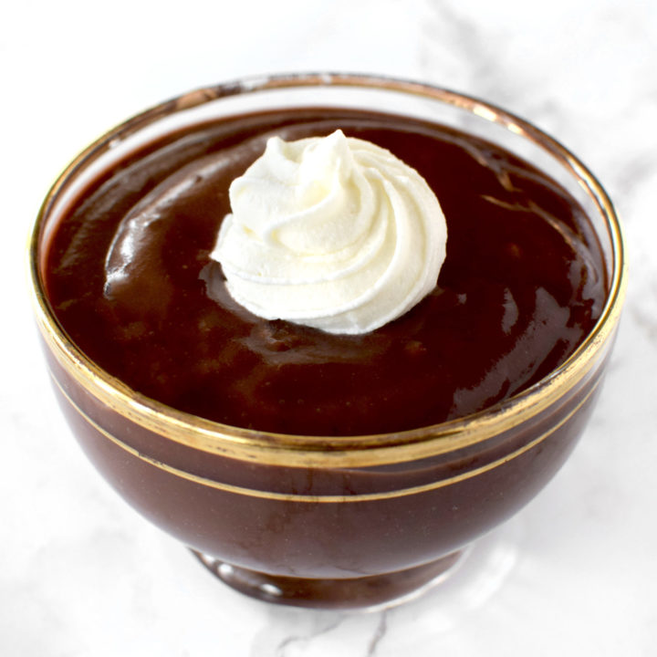 Chocolate pudding in a glass bowl on a white marble counter