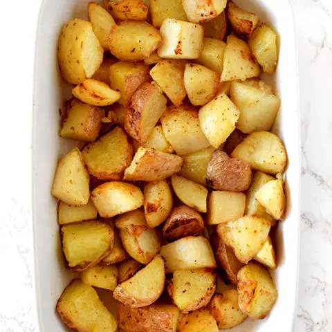 garlic roasted potatoes in a white casserole dish on a white marble counter