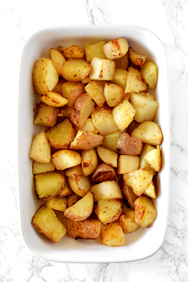 garlic roasted potatoes in a white casserole dish on a white marble counter
