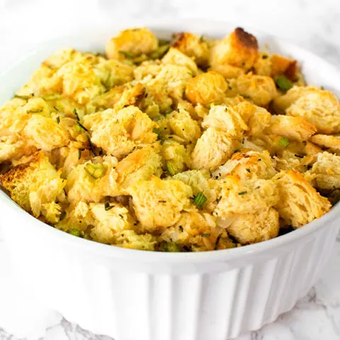 Dairy free stuffing or dressing in a white casserole dish on a white marble counter