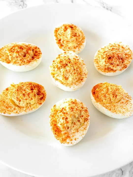 deviled eggs on a white plate on a white marble counter