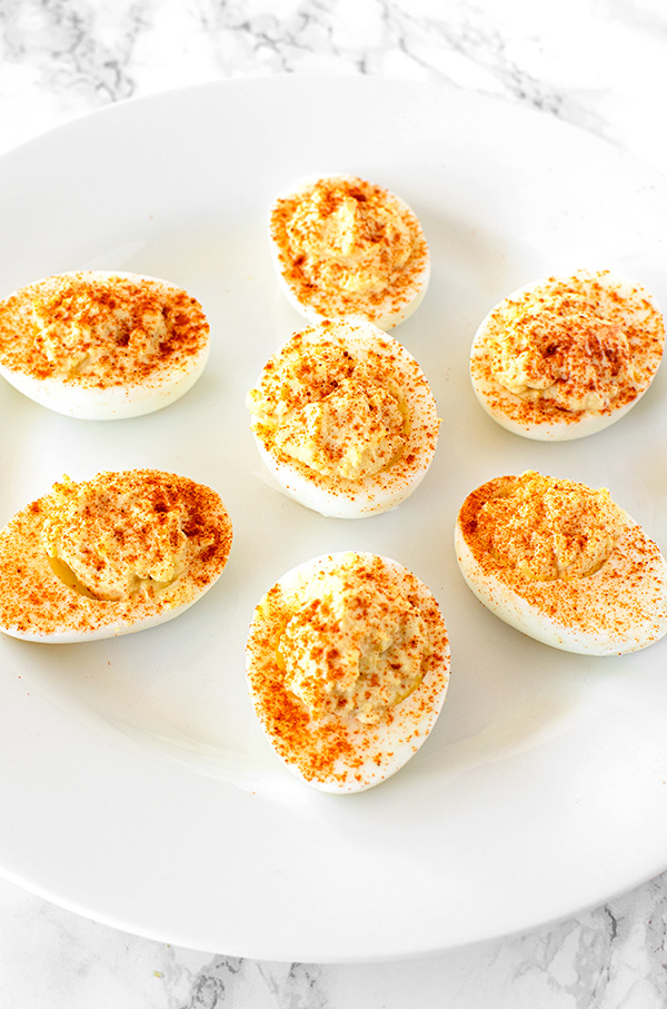 deviled eggs on a white plate on a  white marble counter