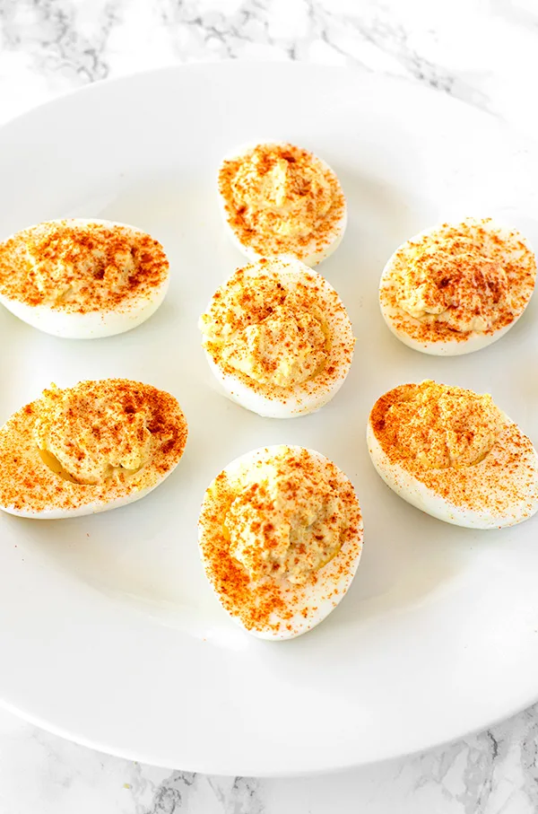 deviled eggs on a white plate on a white marble counter
