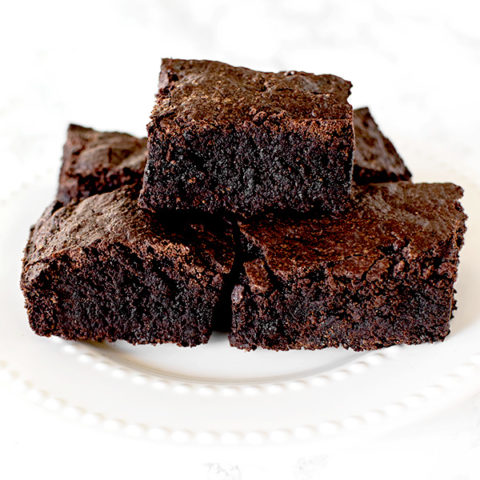 Brownies on a white plate on a white marble counter