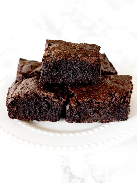 Brownies on a white plate on a white marble counter