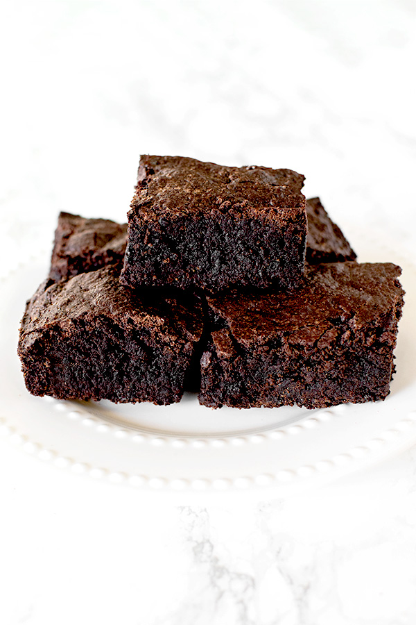 Brownies on a white plate on a white marble counter