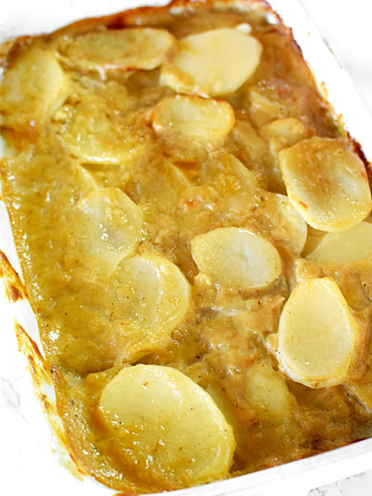 dairy free scalloped potatoes in a white casserole dish on a white marble counter