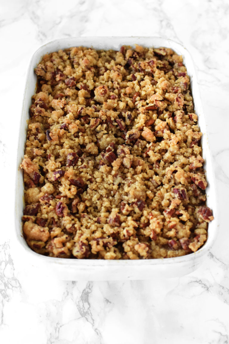sweet potato casserole with pecans in a white casserole dish on a white marble counter