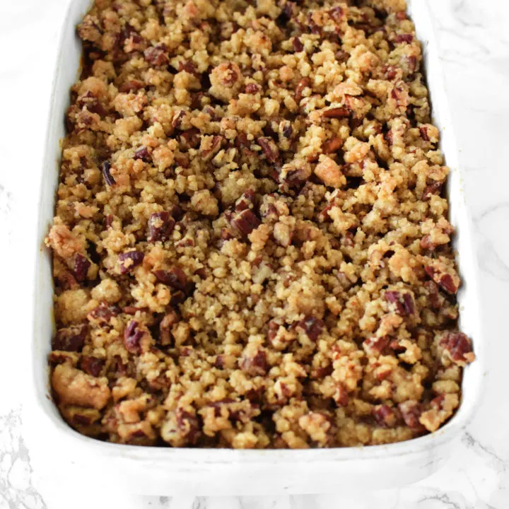 sweet potato casserole with pecans in a white casserole dish on a white marble counter