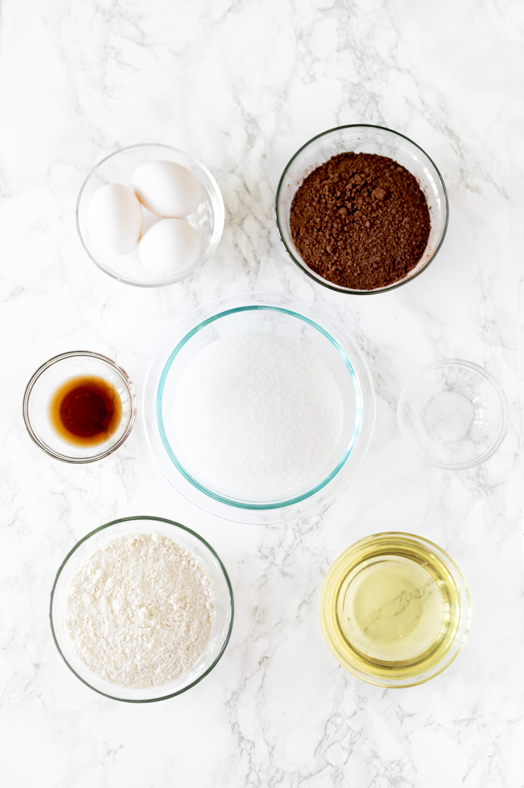 chewy brownie ingredients in little bowls on a white marble counter