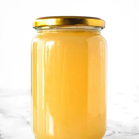 Chicken stock in a jar on a white marble counter