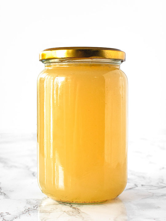 Chicken stock in a jar on a white marble counter
