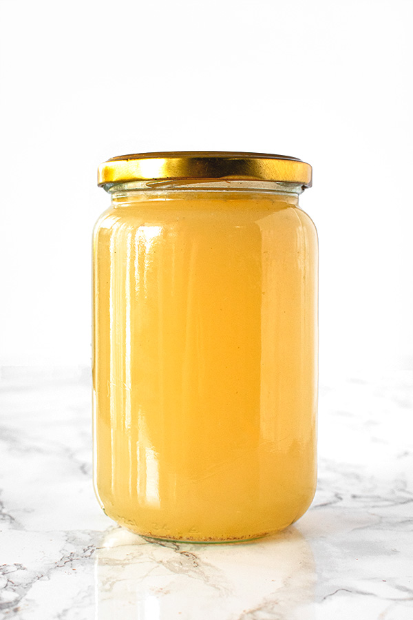 Chicken stock in a jar on a white marble counter