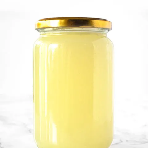 Vegetable stock in a jar on a white marble counter