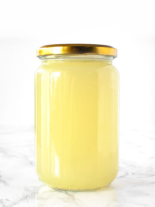 Vegetable stock in a jar on a white marble counter