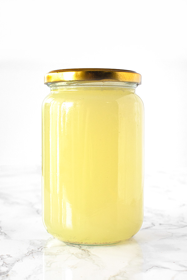 Vegetable stock in a jar on a white marble counter