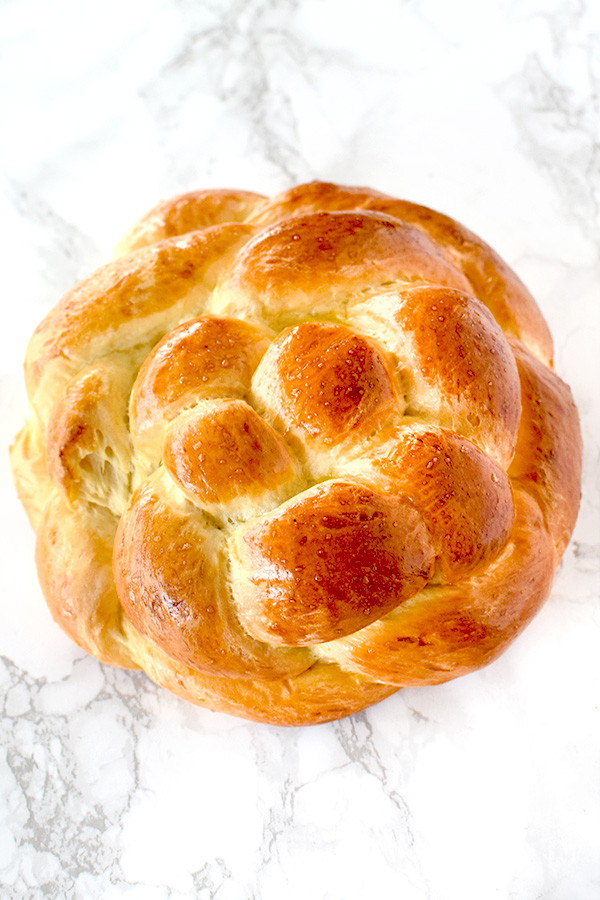 Round honey challah on a white marble counter