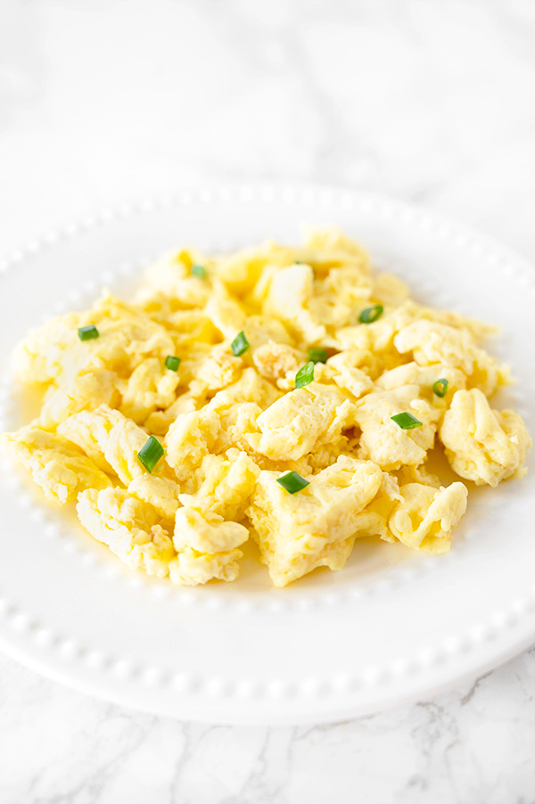 scrambled eggs with mayonnaise on a white plate on a white marble counter