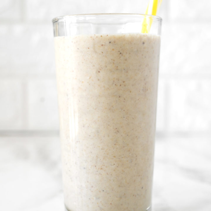 Banana Smoothie with Almond Milk in a glass on a white marble counter with a yellow straw