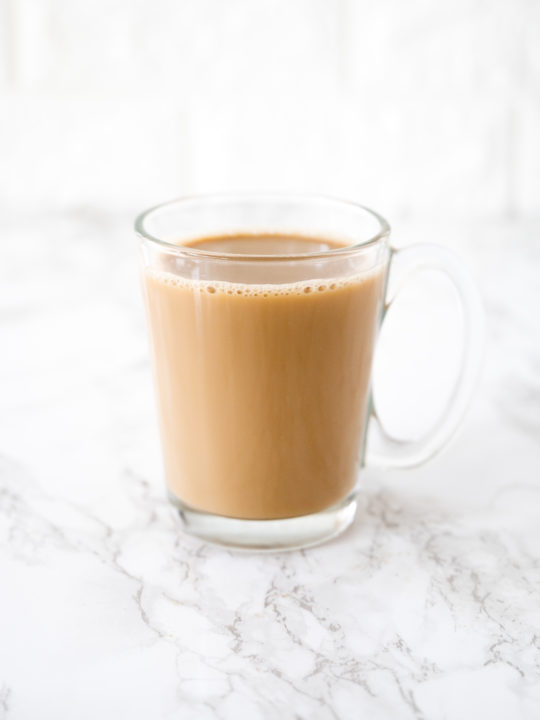 Coffee with oat milk in a glass cup on a white marble counter