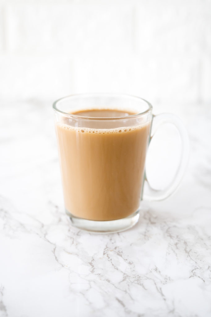 Coffee with oat milk in a glass cup on a white marble counter