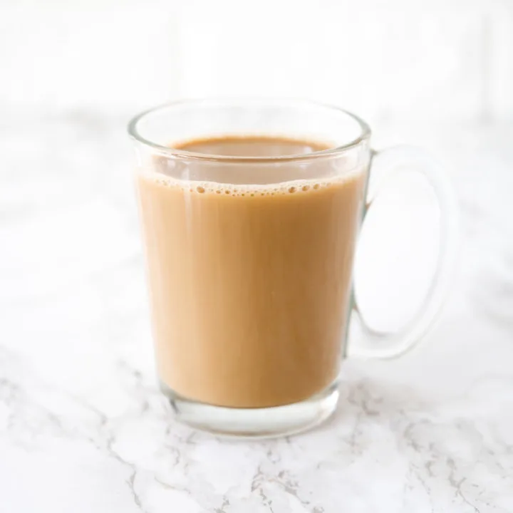 Coffee with oat milk in a glass cup on a white marble counter