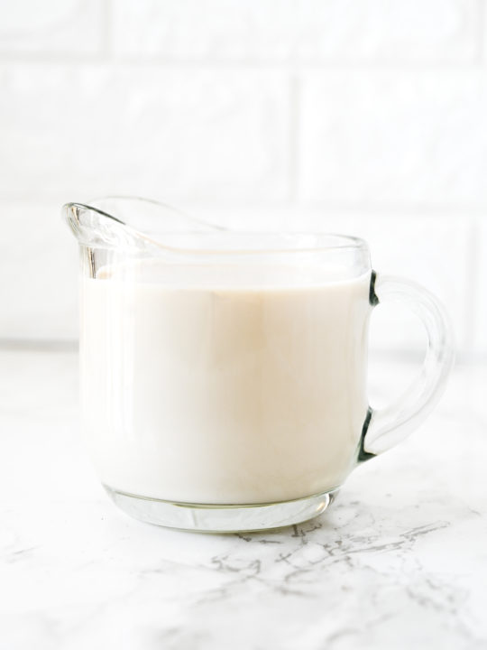 dairy free buttermilk in a glass creamer on a white marble counter