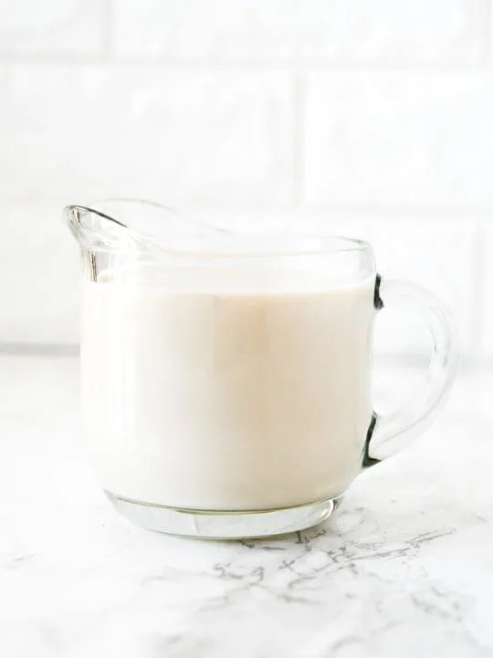 dairy free buttermilk in a glass creamer on a white marble counter