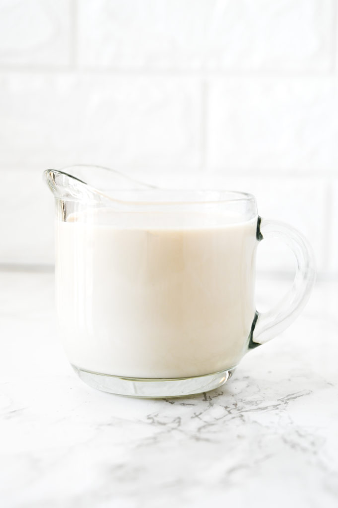 dairy free buttermilk in a glass creamer on a white marble counter