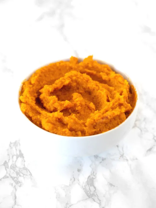 Mashed Sweet Potatoes in a white bowl on a white counter