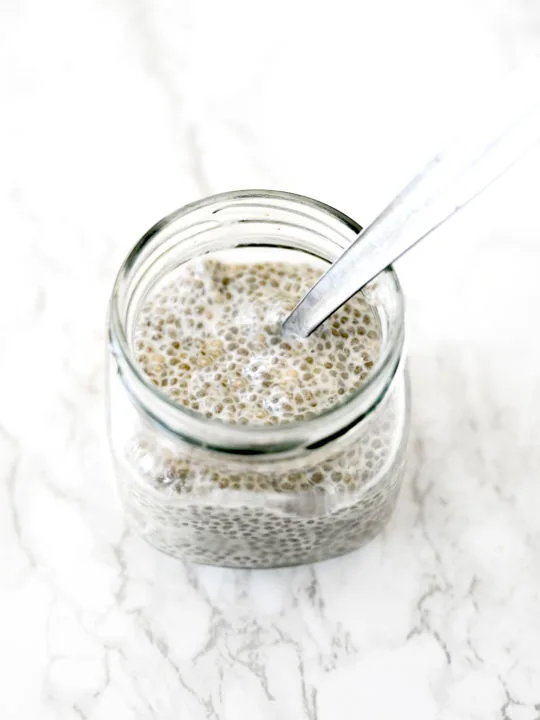 Chia pudding with almond milk in a glass jar on a white marble counter