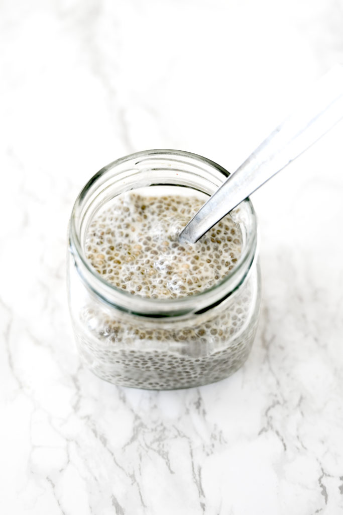 Chia pudding with almond milk in a glass jar on a white marble counter