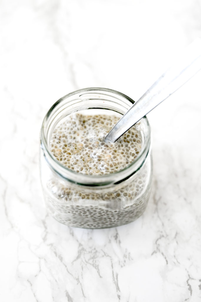 Chia pudding with almond milk in a glass jar on a white marble counter