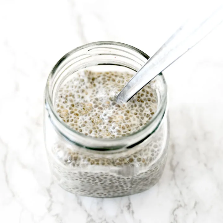 Chia pudding with almond milk in a glass jar on a white marble counter