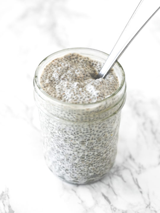 Chia pudding with coconut milk in a glass jar on a white marble counter