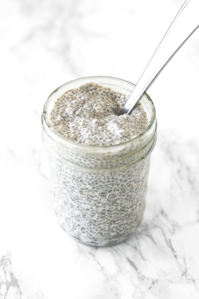 Chia pudding with coconut milk in a glass jar on a white marble counter