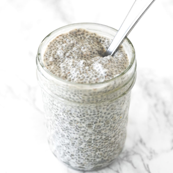 Chia pudding with coconut milk in a glass jar on a white marble counter