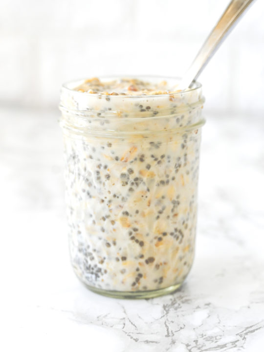 Overnight Oats in a jar with a spoon on a white marble counter
