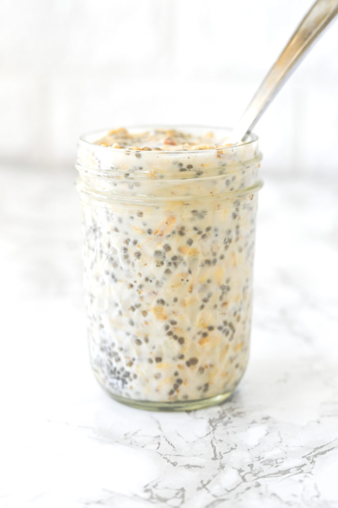 Overnight Oats in a jar with a spoon on a white marble counter