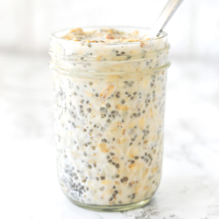 Overnight Oats in a jar with a spoon on a white marble counter