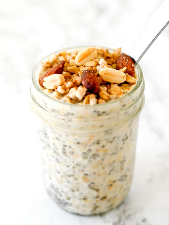 Overnight Oats with Muesli in a jar with a spoon on a white marble counter