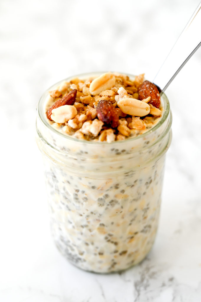 Overnight Oats with Muesli in a jar with a spoon on a white marble counter