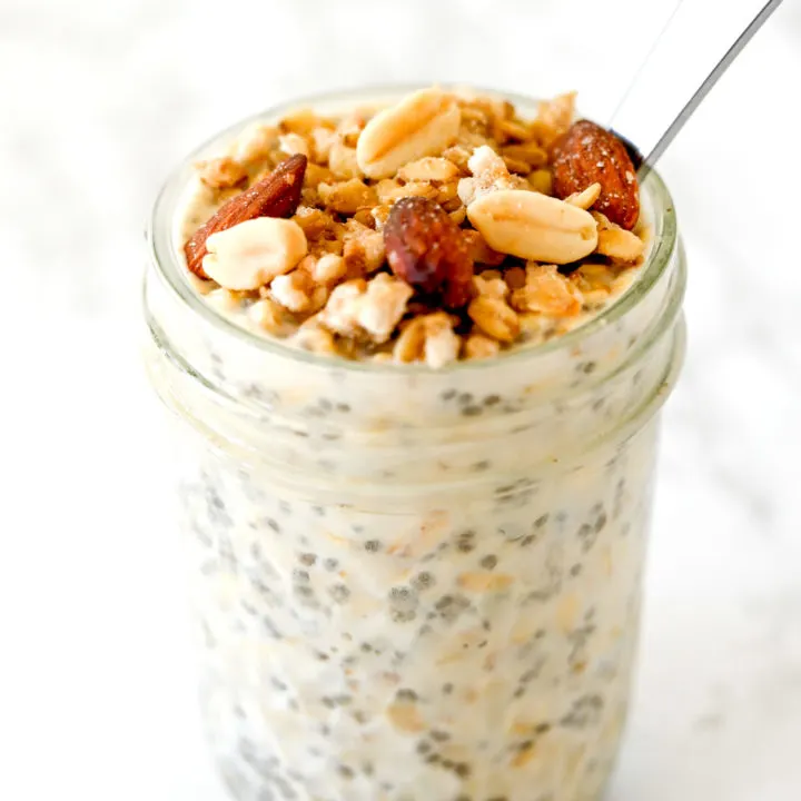 Overnight Oats with Muesli in a jar with a spoon on a white marble counter